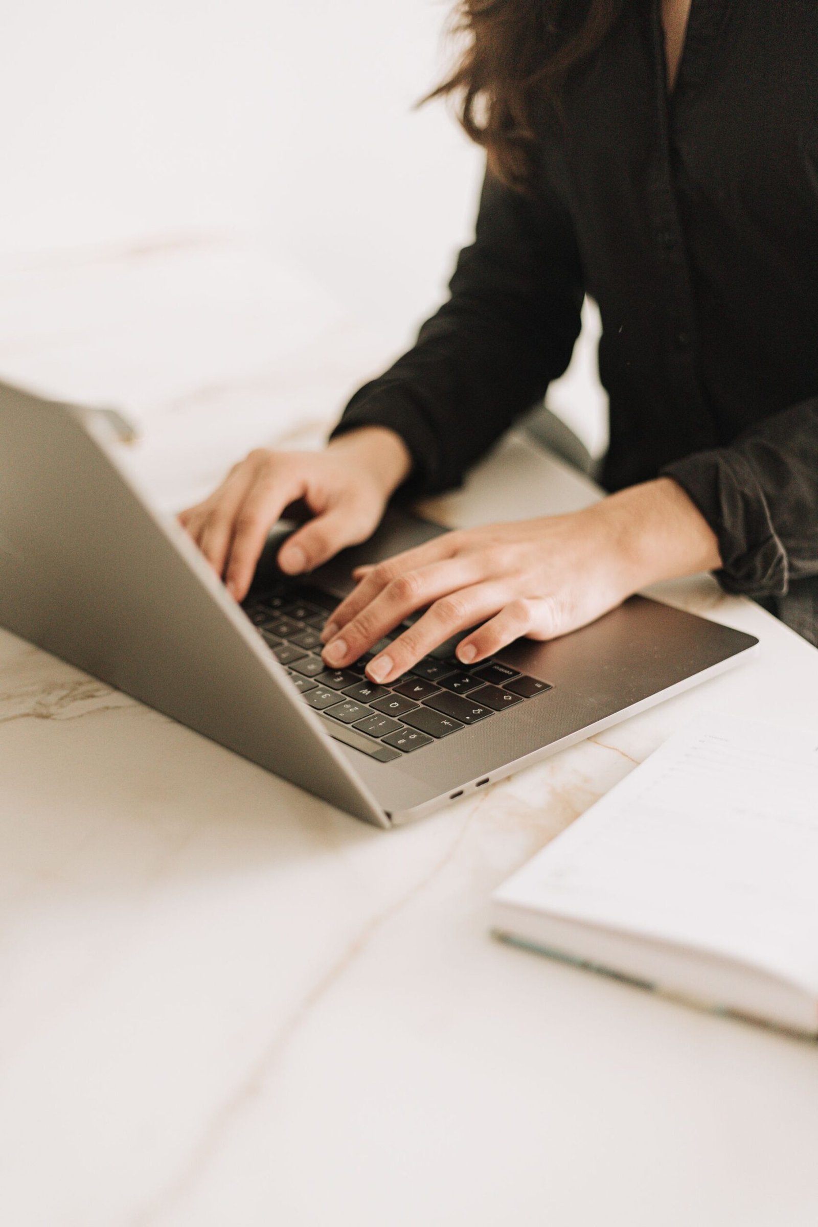 Woman typing on a laptop in a bright, modern workspace.