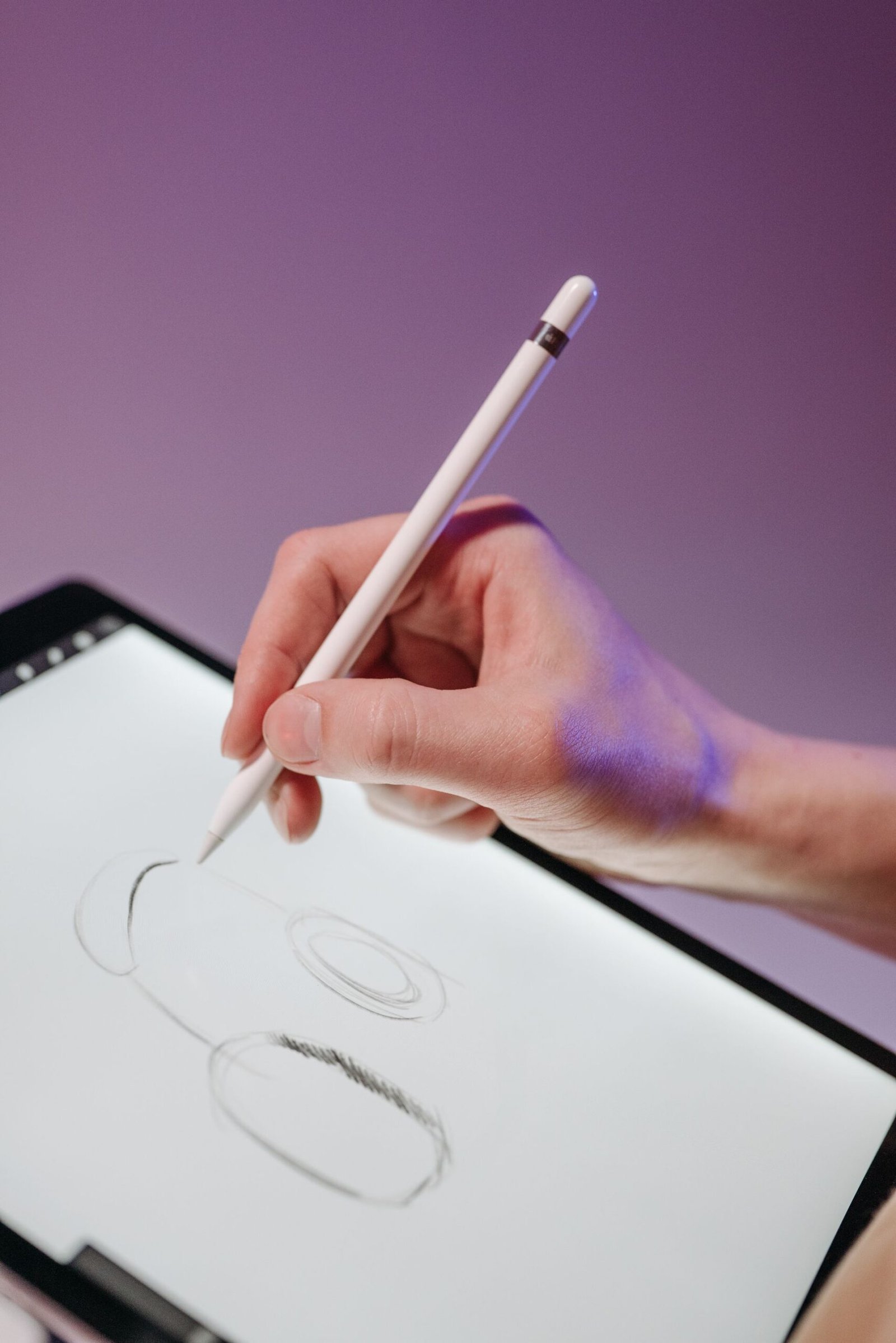 A hand uses a stylus to draw on a digital tablet.