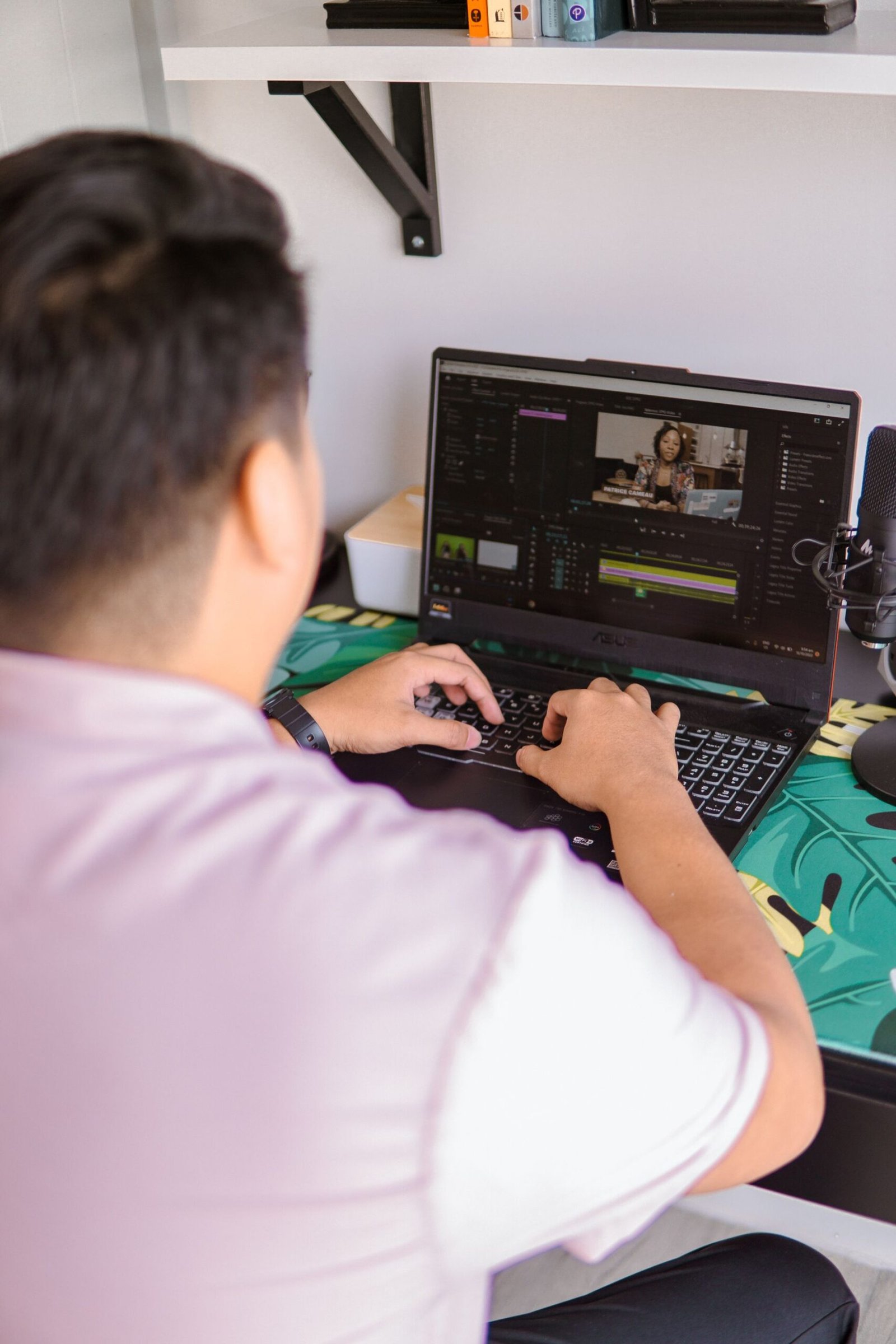 Man editing video on a laptop in a home workspace.
