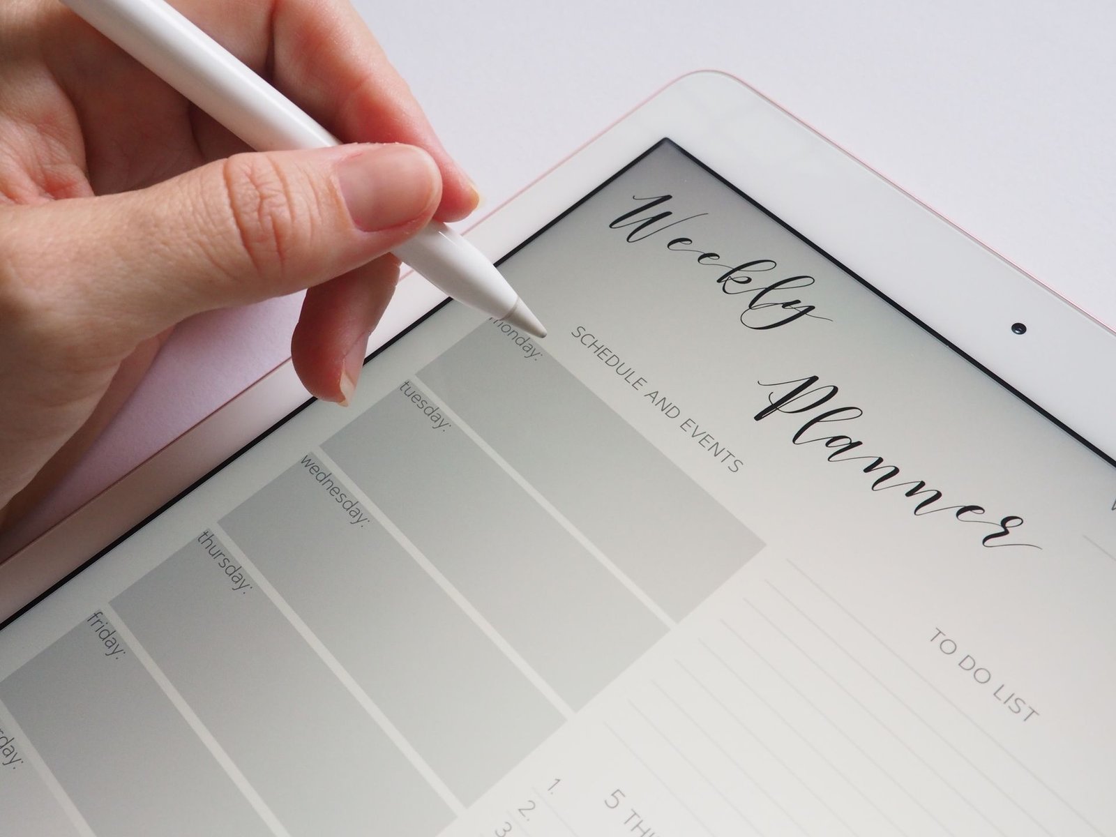 A stylus writing in a digital weekly planner on a tablet screen.