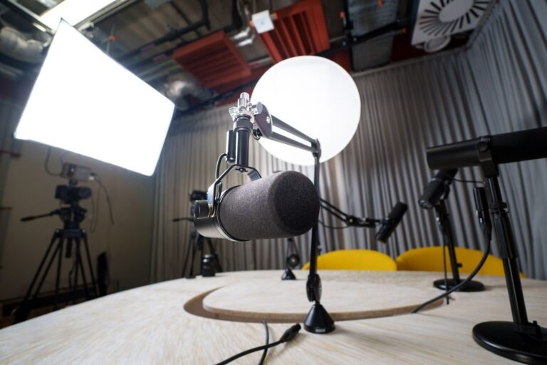 A modern podcast recording studio with microphones, chairs, and lighting equipment.