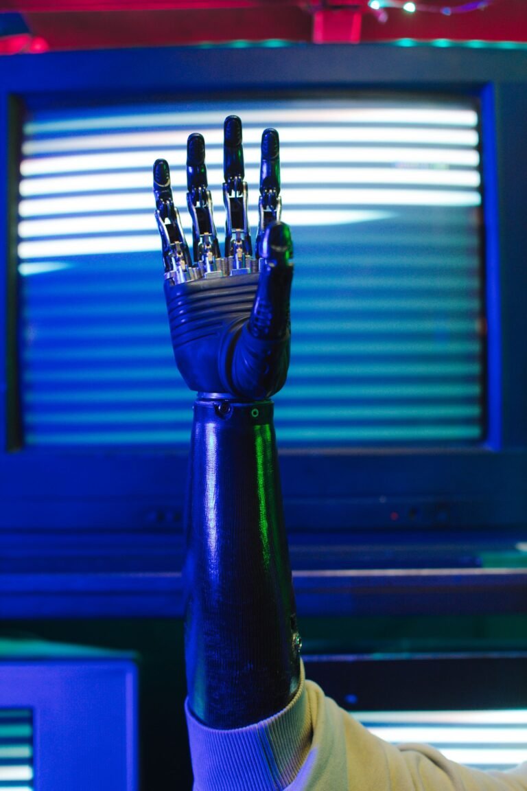 Close-up of a bionic prosthetic hand raised against a dark background.