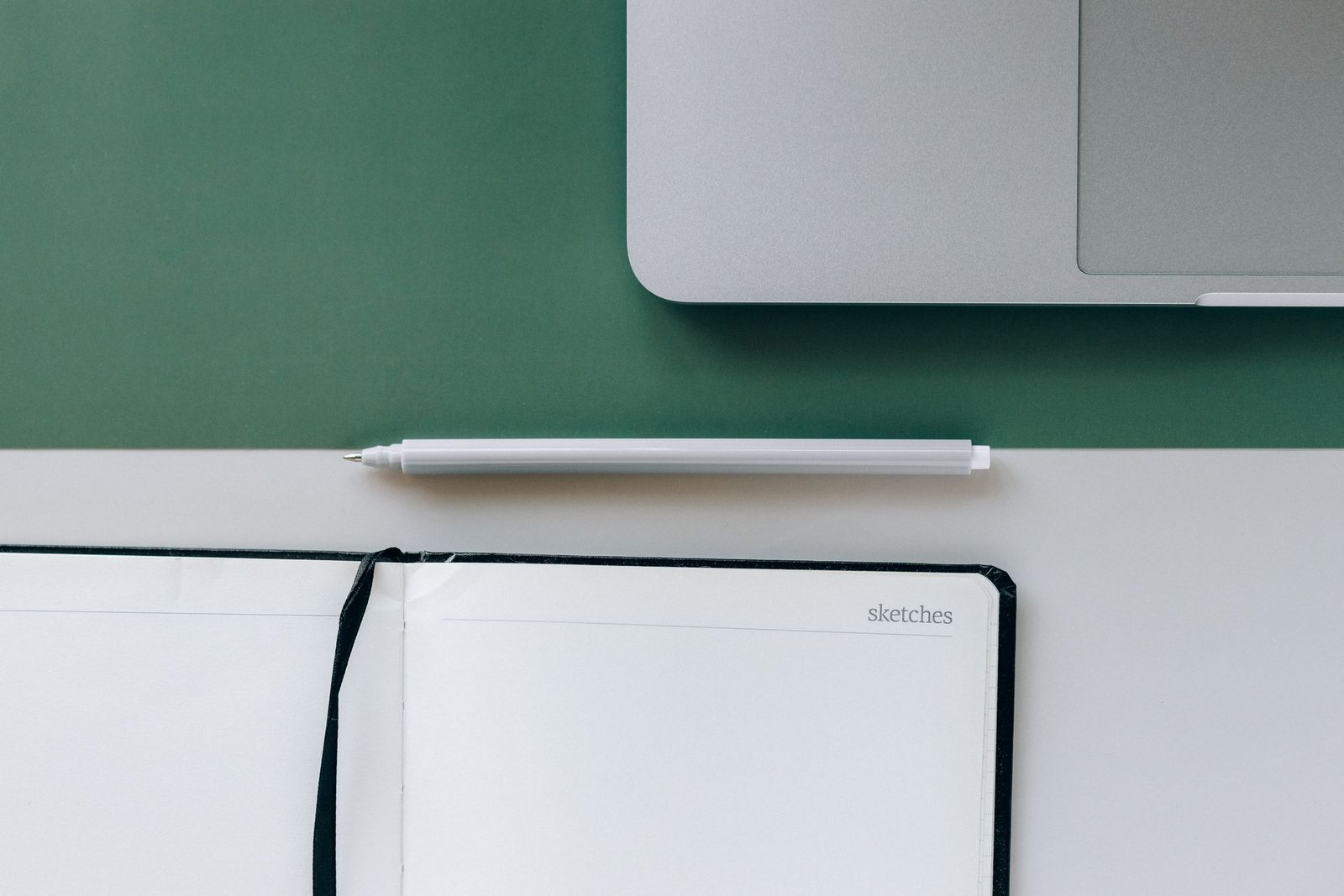 Minimalist desk setup with a notebook, pen, and laptop.