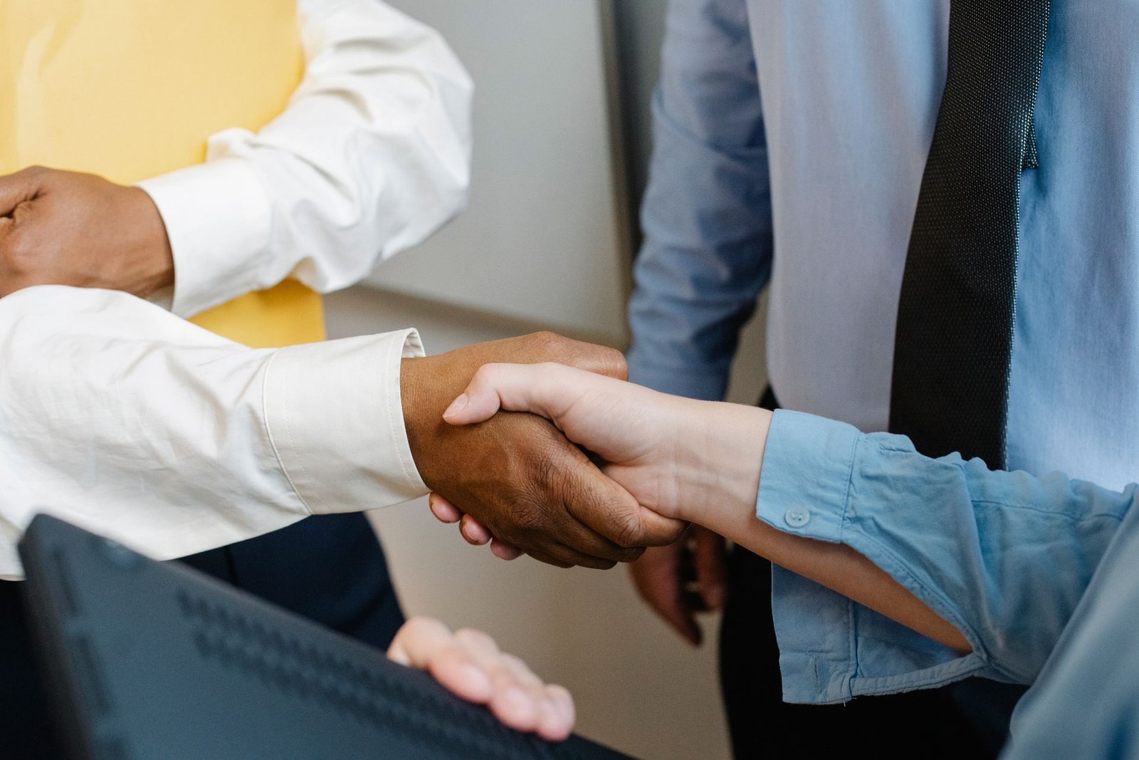 Multiracial colleagues shaking hands at work.