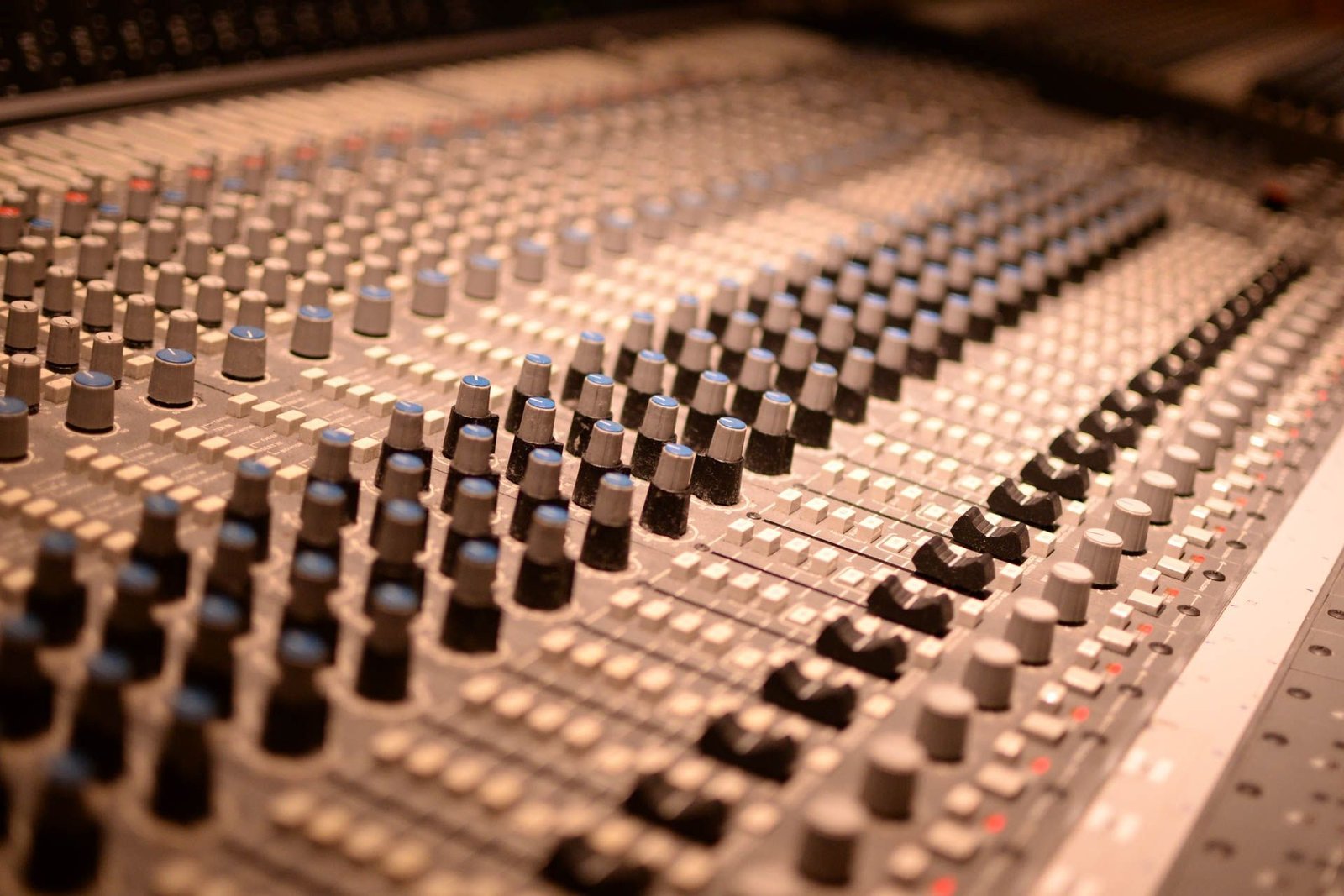 Detailed view of an analog audio mixing console with knobs and sliders.