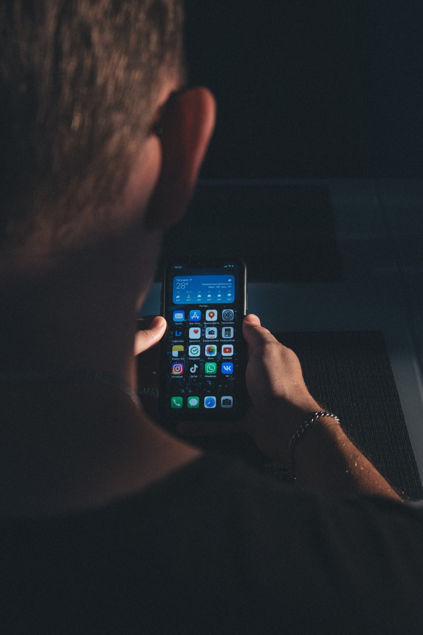 Close-up of a hand holding a smartphone showing its home screen.