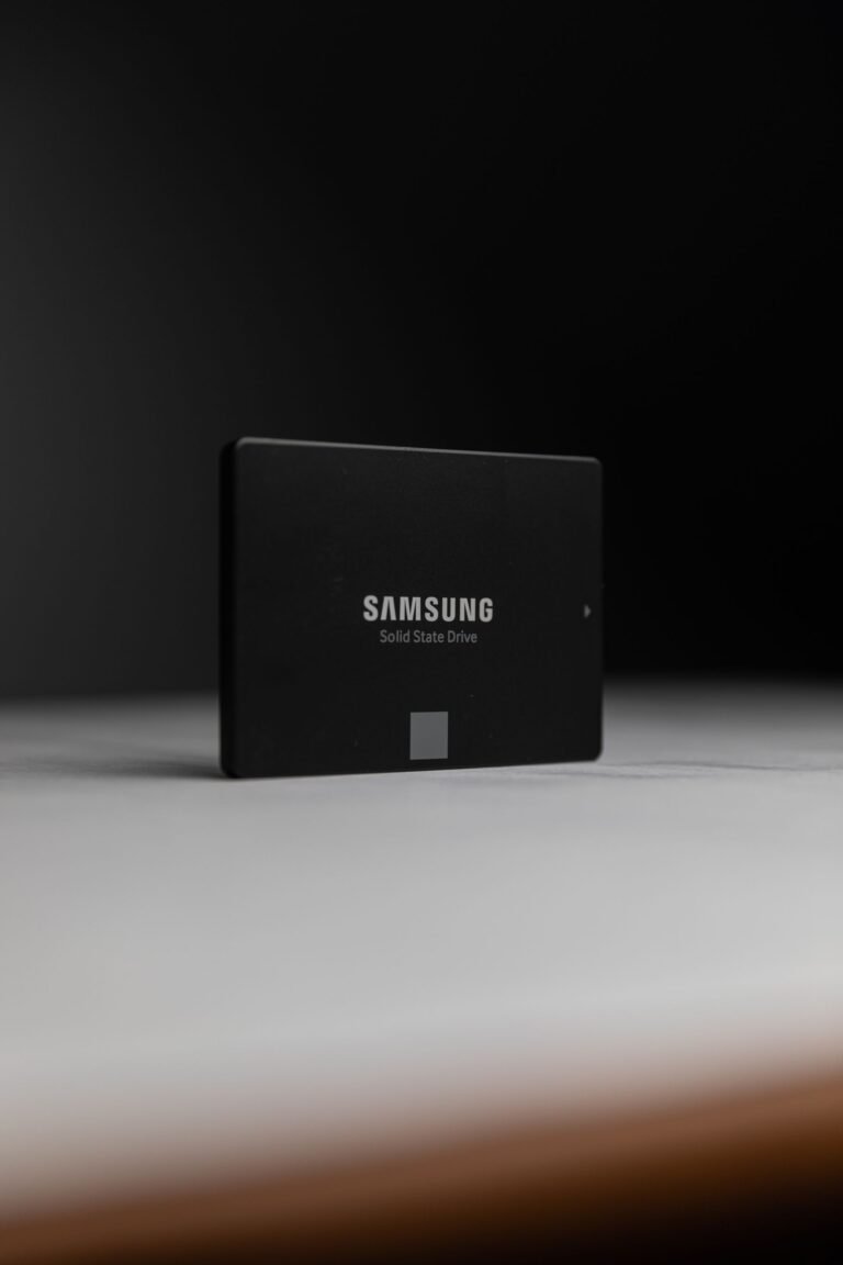 A solid-state drive held above an open laptop during an upgrade.