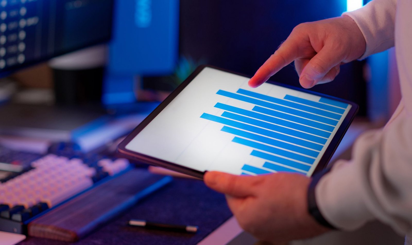 Business professional analyzing a bar chart on a tablet in an office setting.