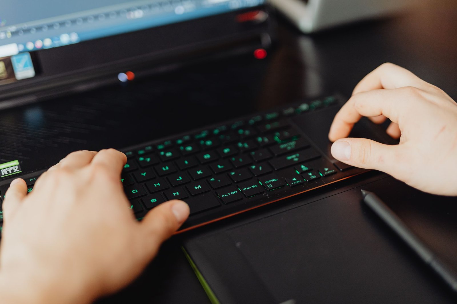 Closeup of hands typing on an RGB backlit keyboard in a modern office.