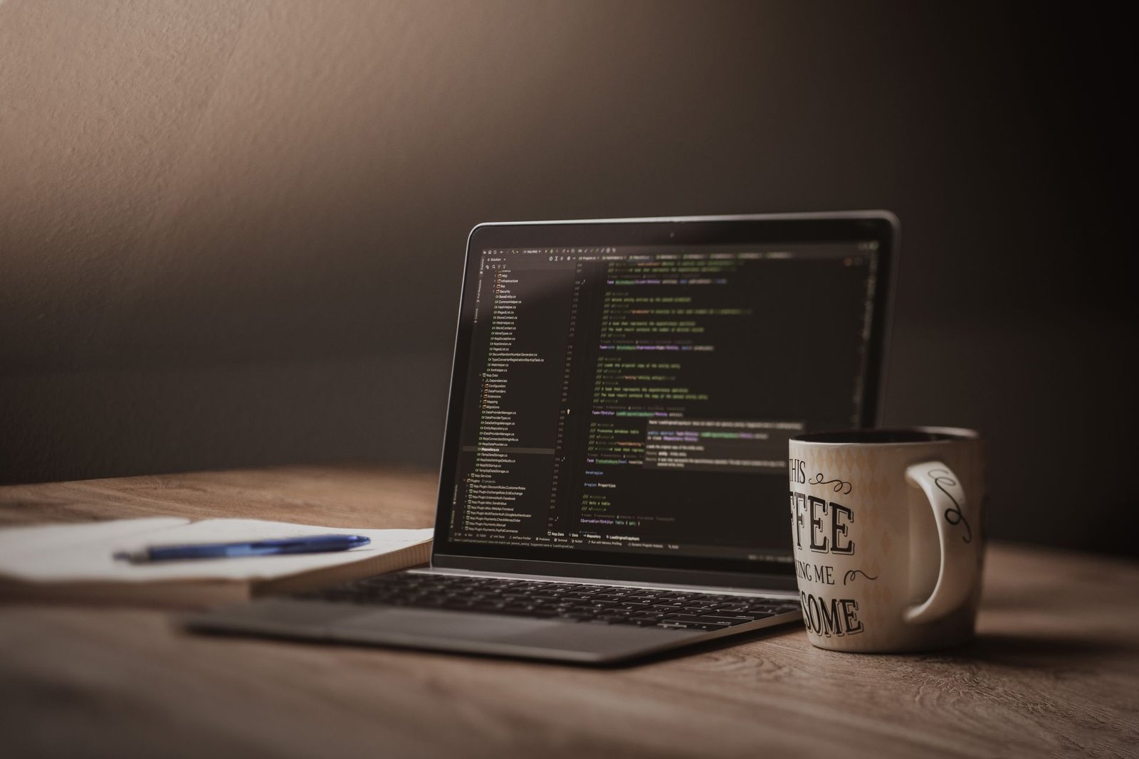 A comfortable workspace with a laptop showing code, a coffee mug, and a notebook.