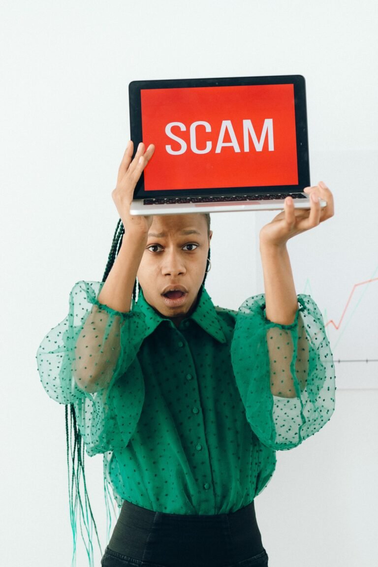 Woman holding a laptop showing a scam alert message on screen.