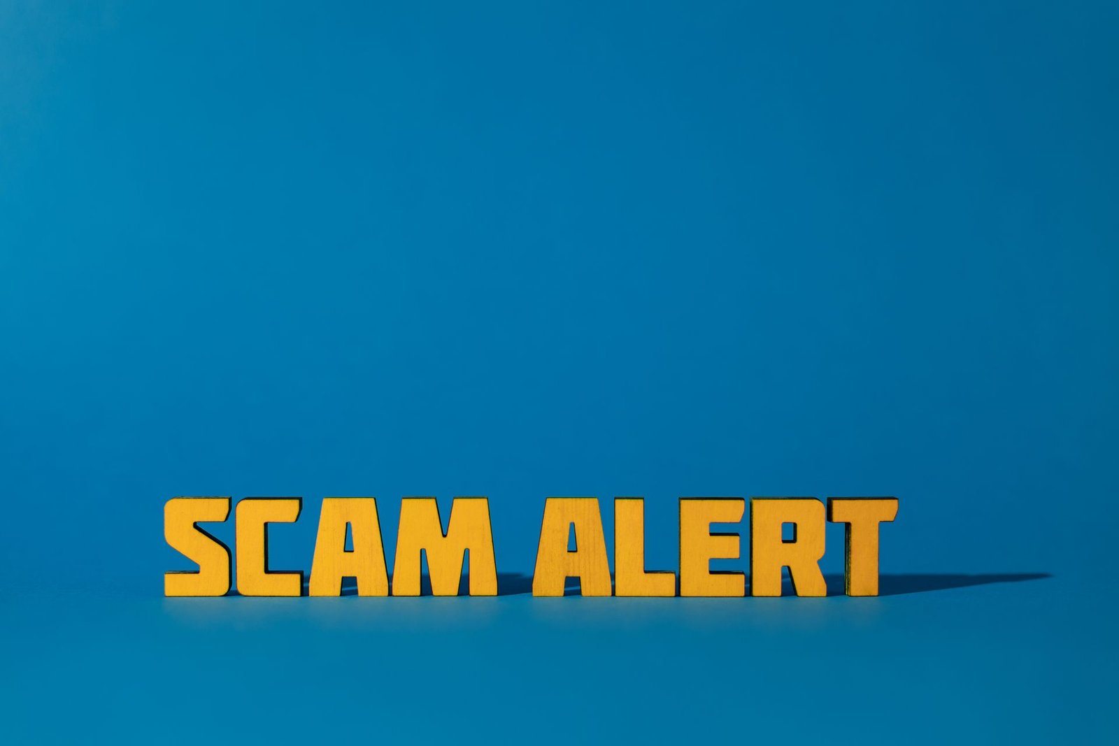 The words Scam Alert in bold yellow letters on a blue background.
