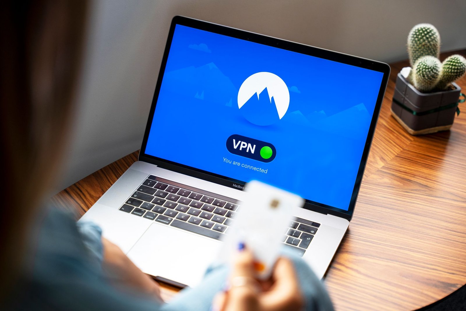 Person using a VPN on a laptop at a wooden table.