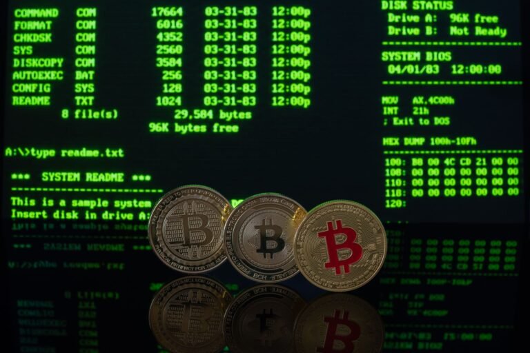 Bitcoin coins in front of a vintage computer screen showing code.