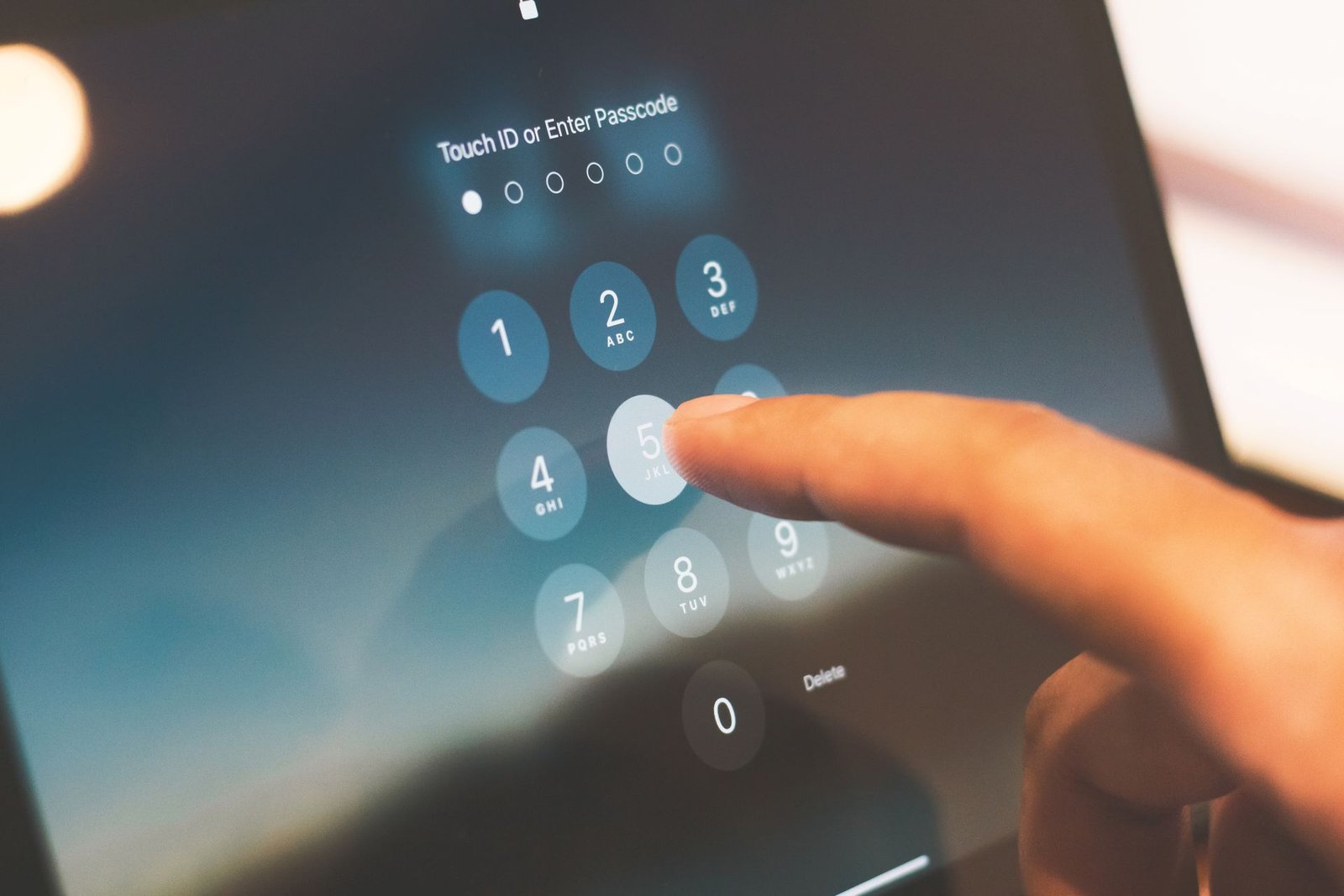 Finger entering a passcode on a smartphone security screen.