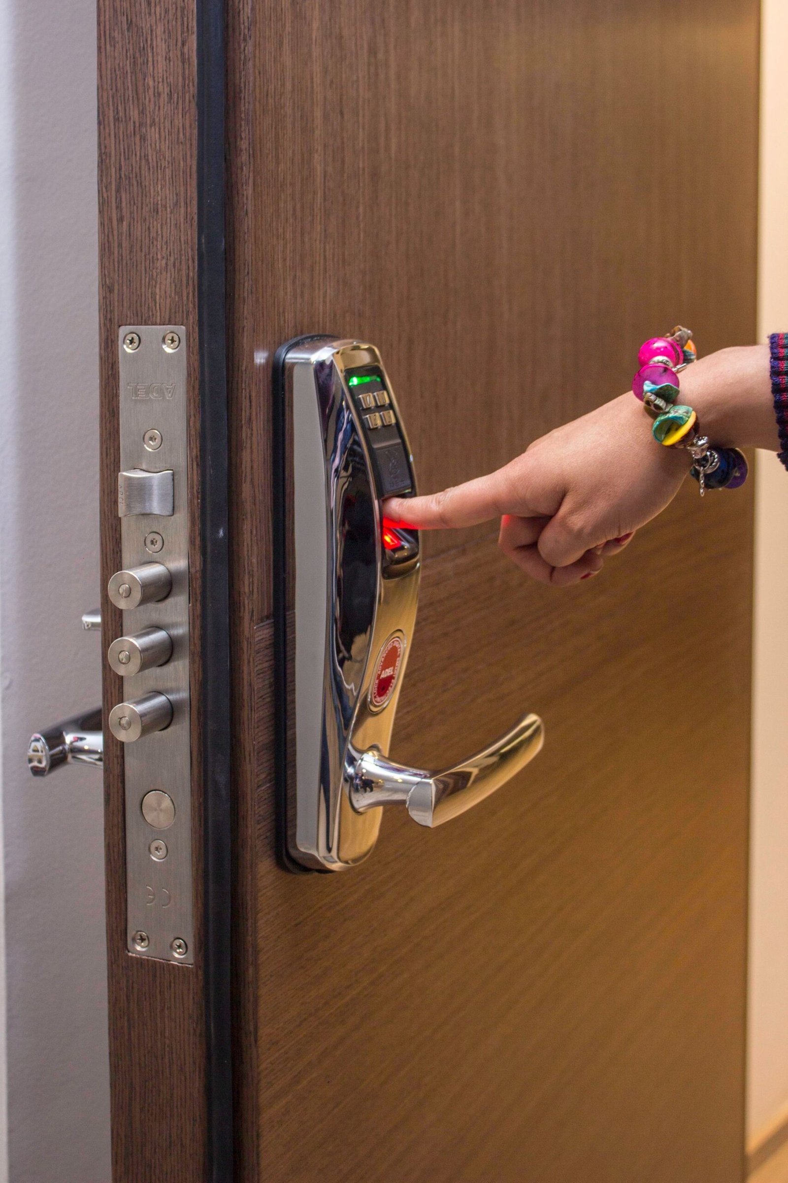 Hand using fingerprint access on a digital door lock.