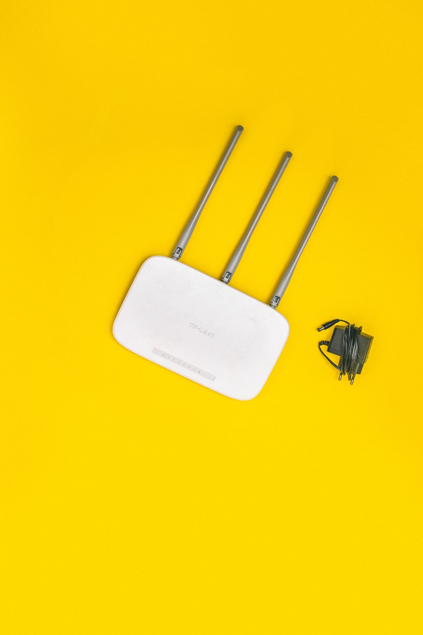 White WiFi router with three antennas on a yellow background.