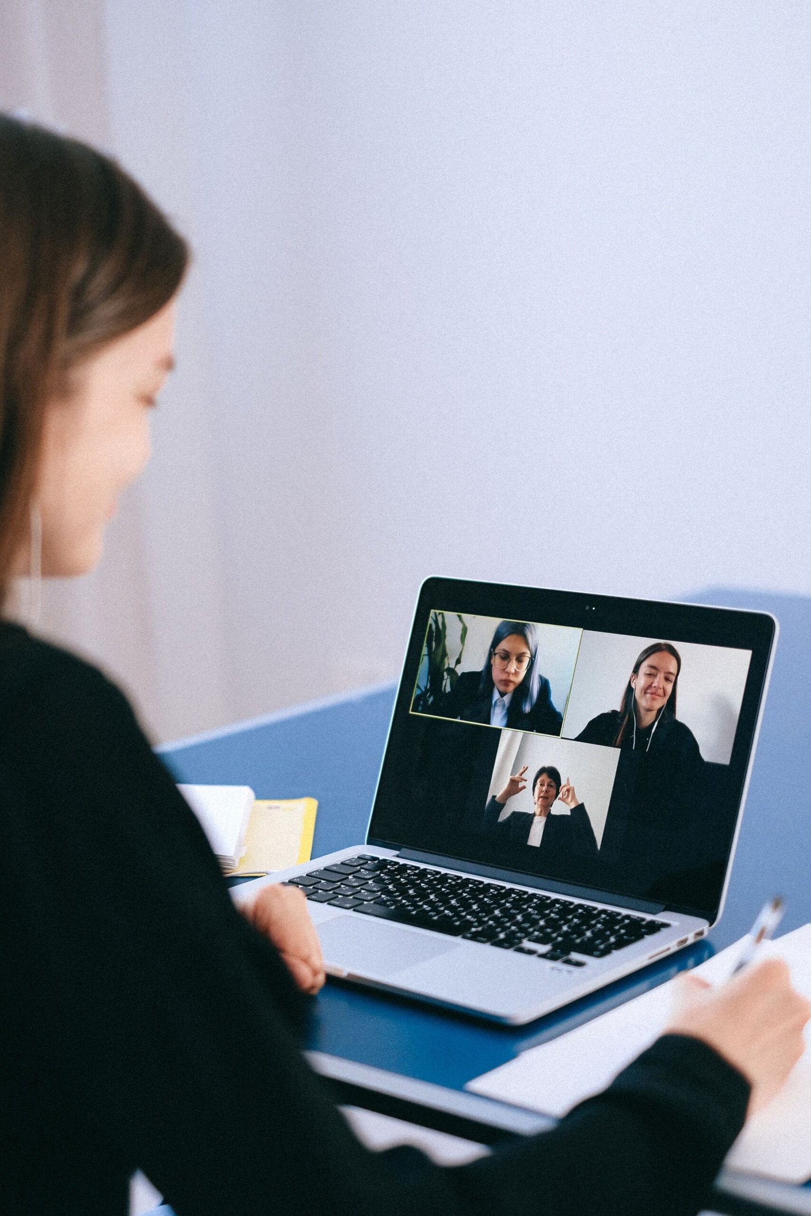 A woman in a virtual meeting with colleagues via video call on her laptop.