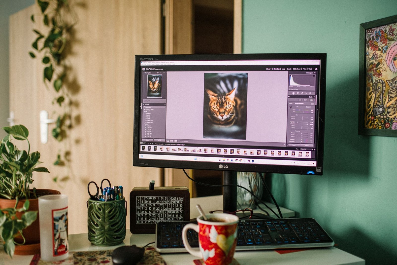 A home office desk with a monitor displaying photo editing software.
