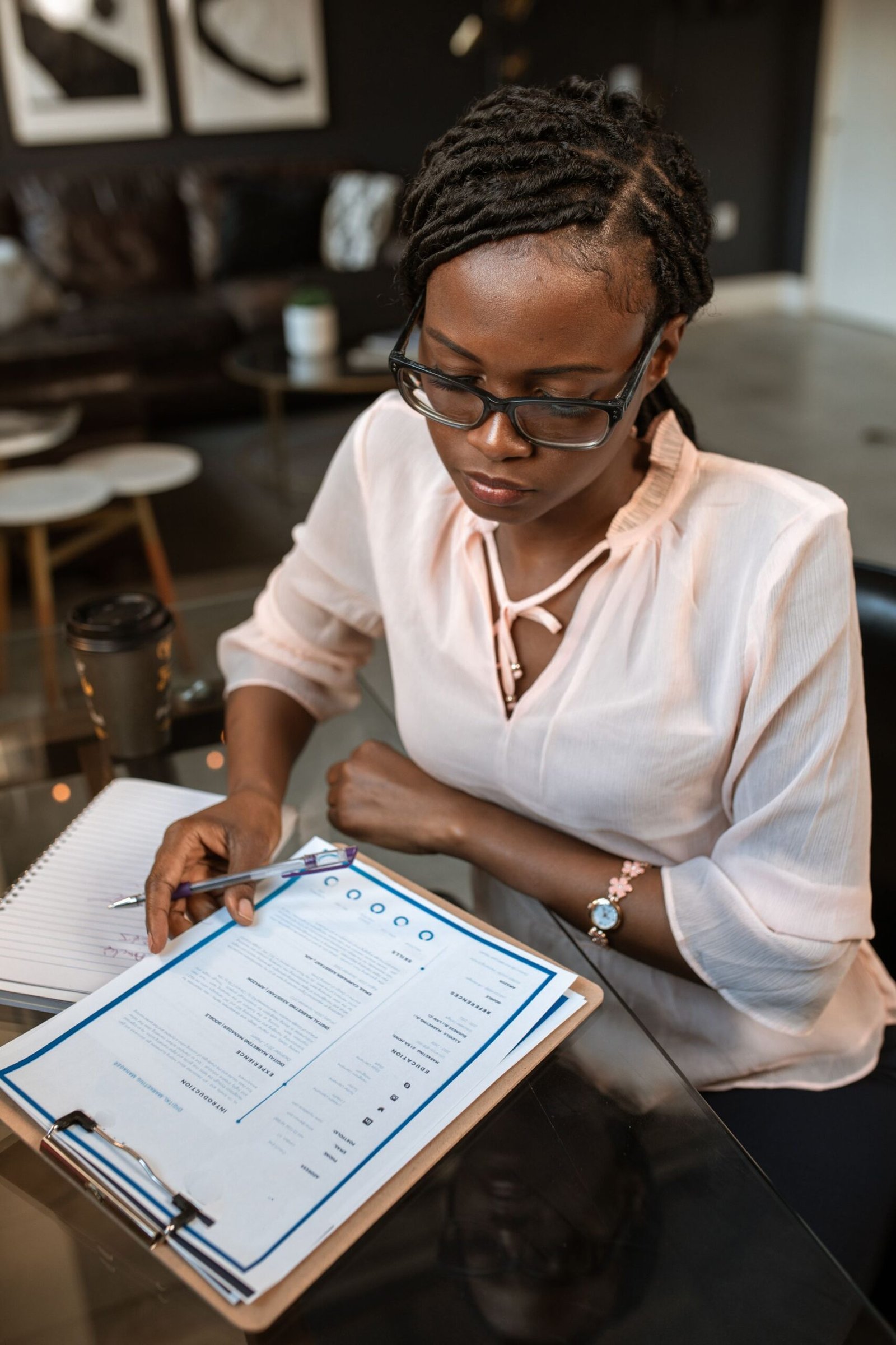 A woman carefully reviewing printed documents, like a hiring manager scanning a resume.