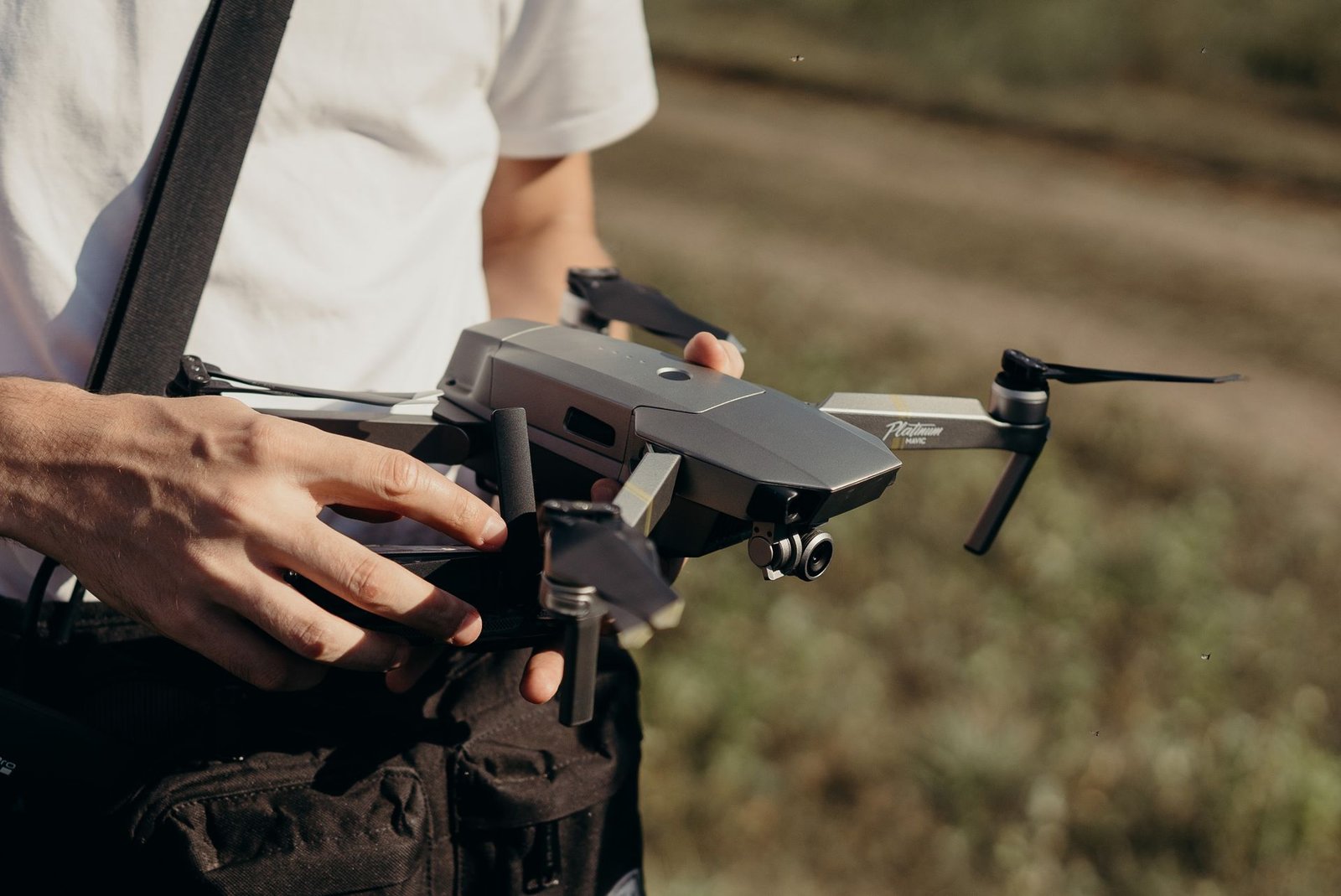 Close-up of a man holding a drone outdoors, preparing for takeoff.