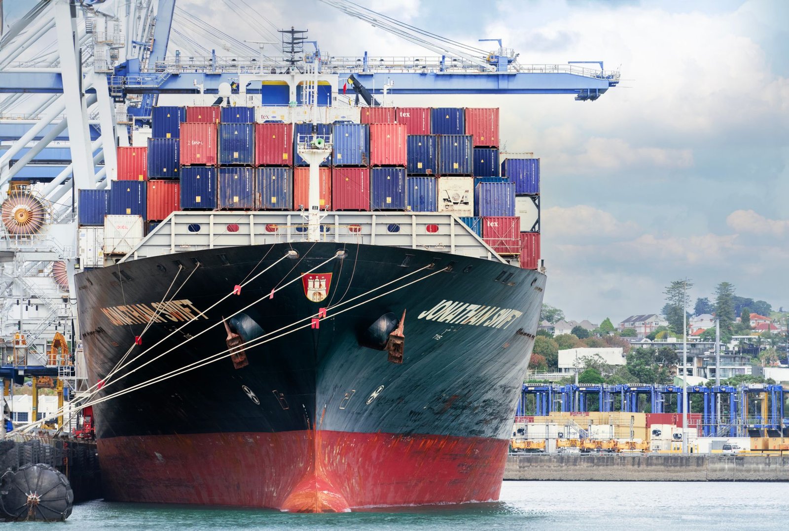A large cargo ship loaded with stacked shipping containers at a port.