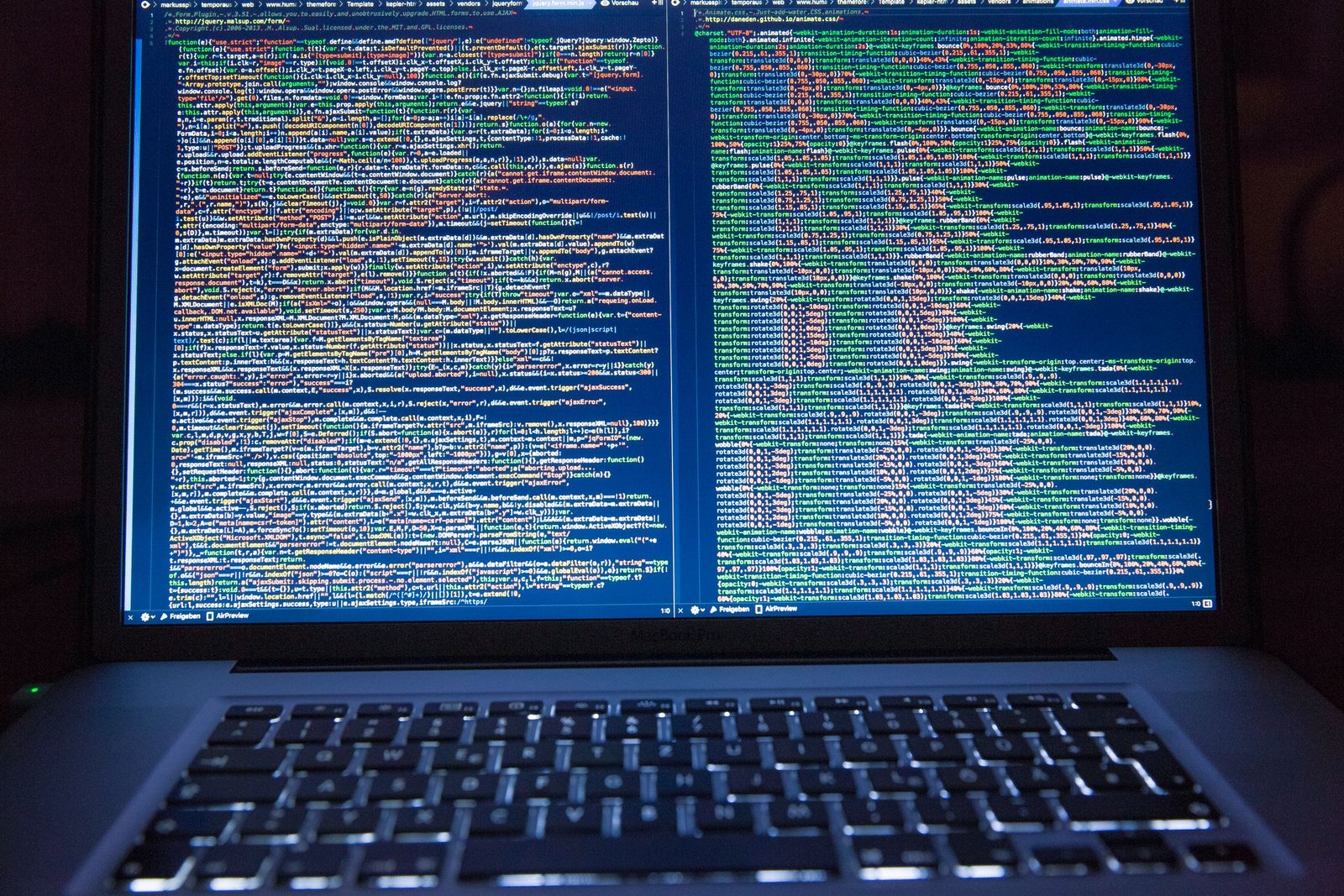A black laptop displaying lines of computer code on its screen.