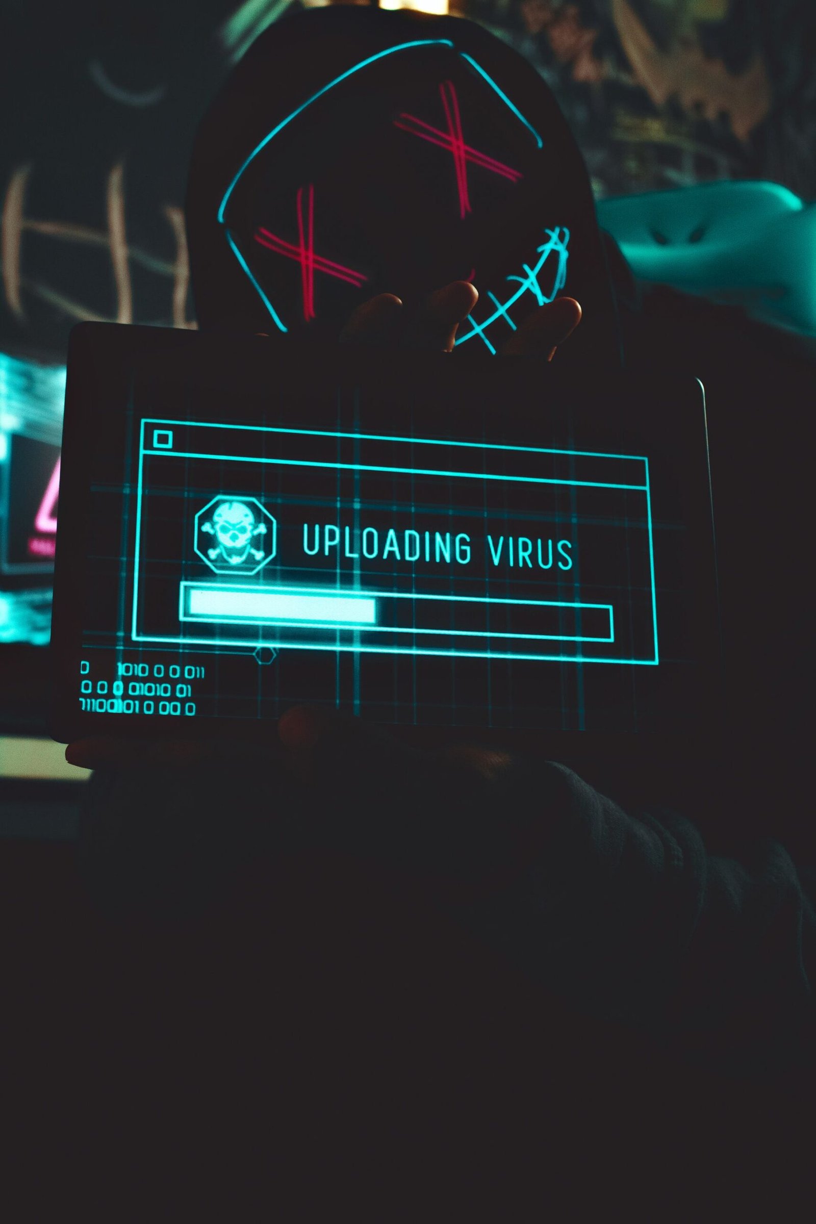 A person in a dark room holding a tablet showing a virus warning screen.