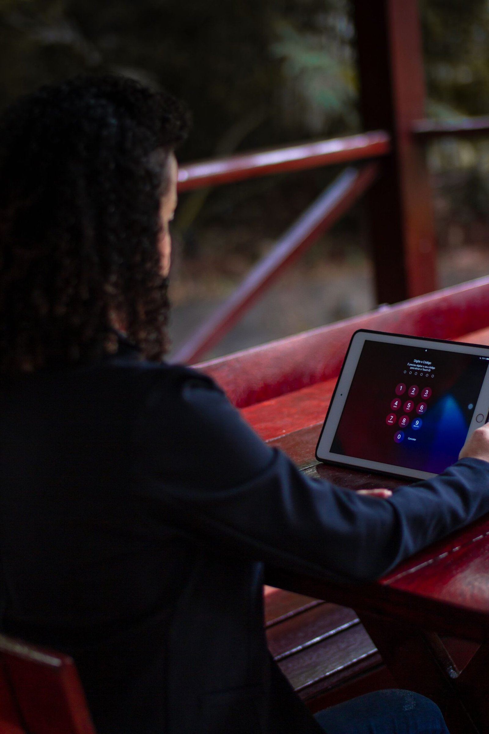 A person unlocking a tablet showing a password entry screen outdoors.