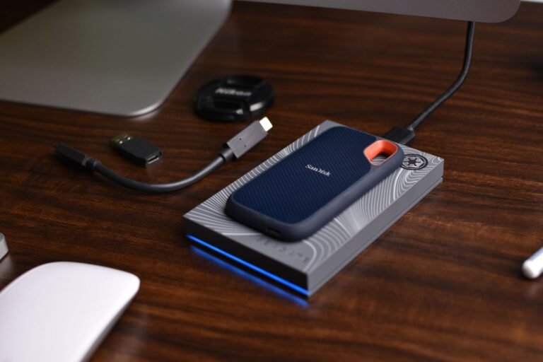 A portable SSD external drive with USB accessories on a wooden desk.