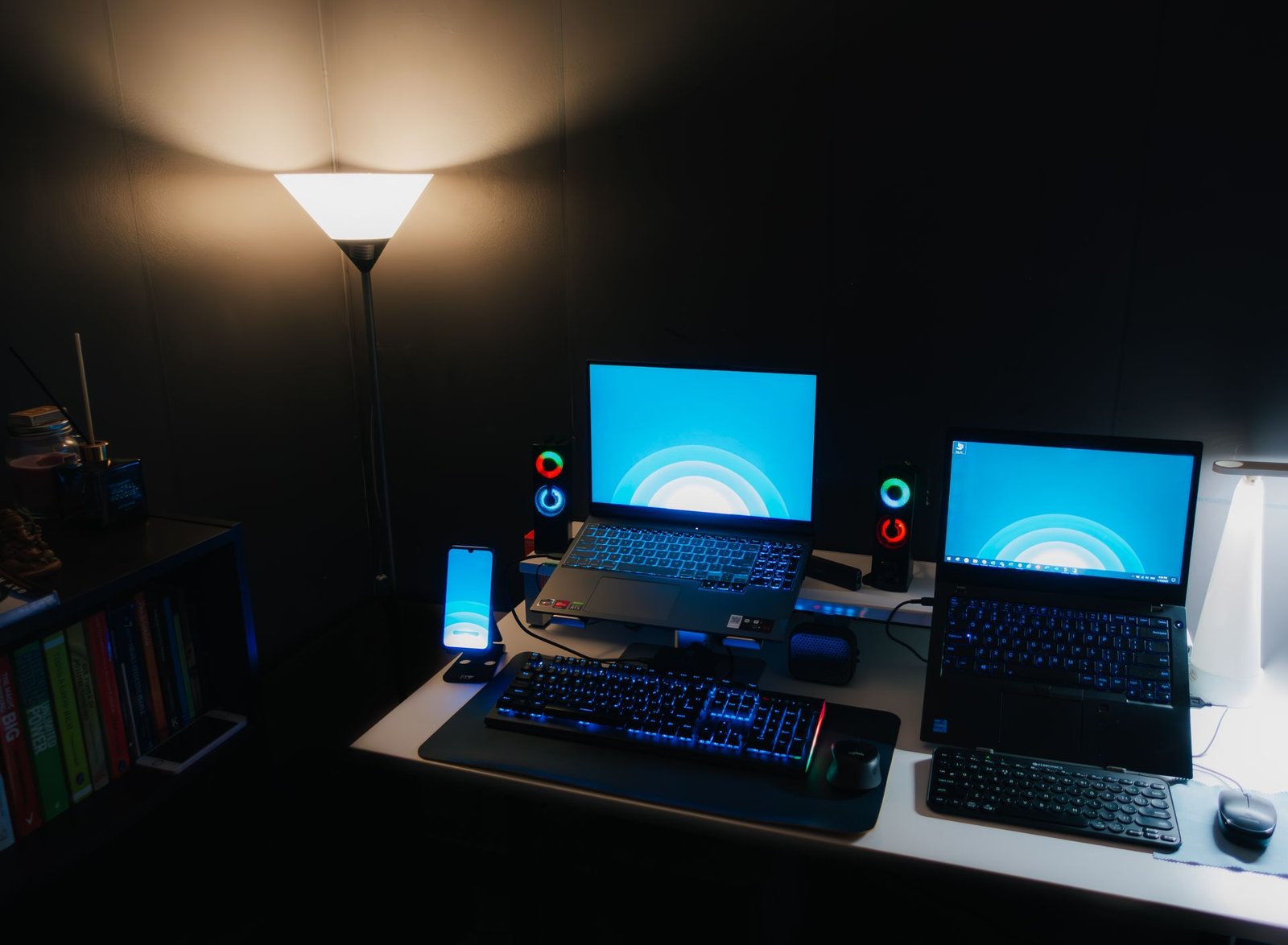 Laptop screens glowing blue in a dark room.