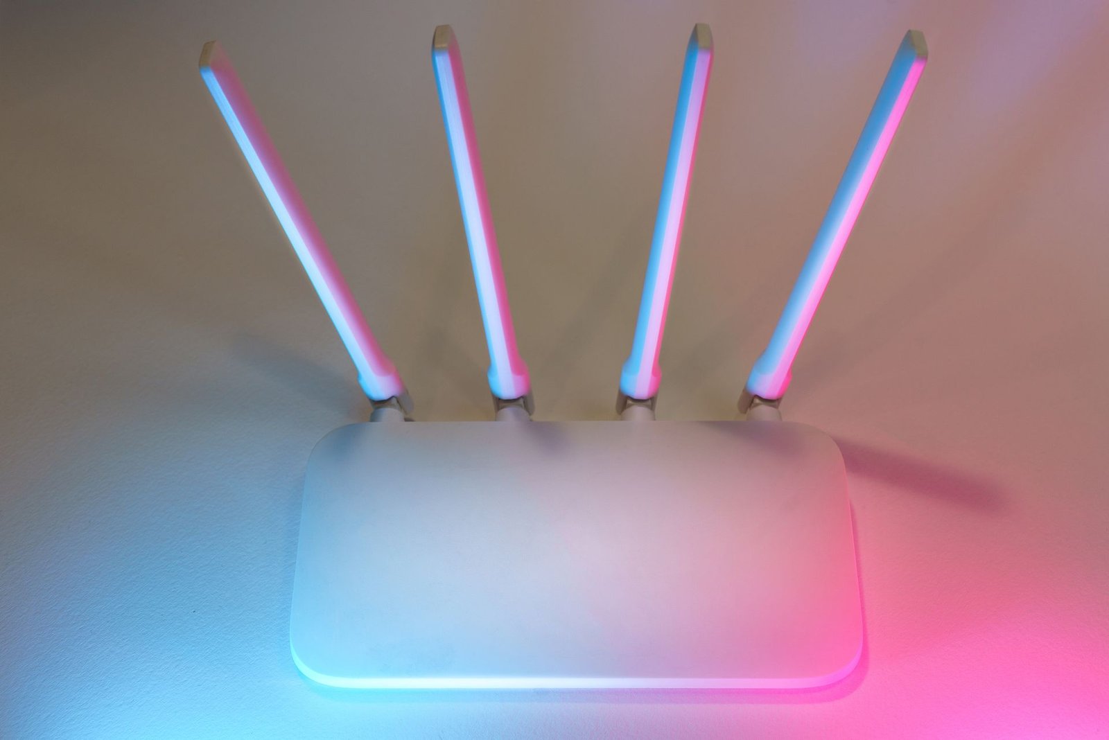 A sleek white wireless router with four antennas in a softly lit room.