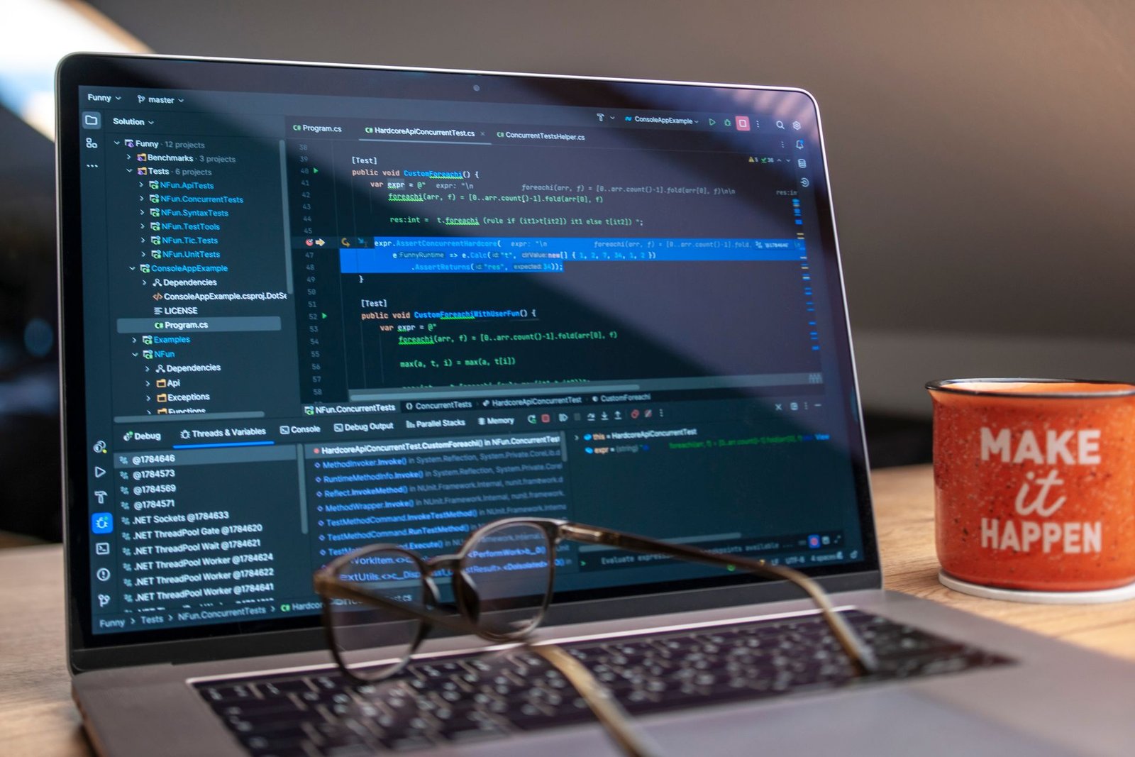 A developer's workspace with a laptop showing a code editor, a notebook, and a coffee mug beside it.