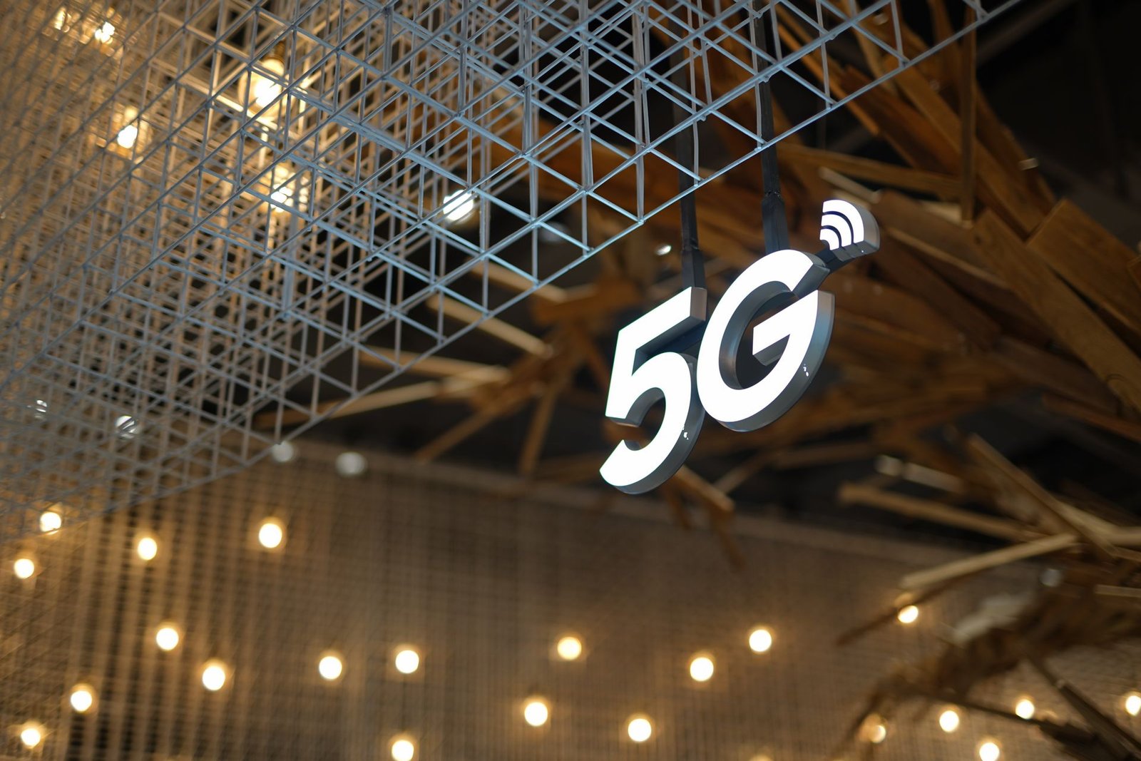 An illuminated 5G sign glowing under a modern geometric ceiling.