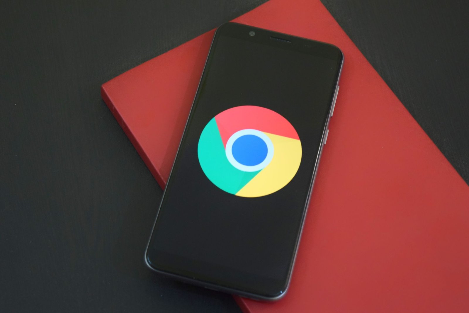 A smartphone with a glowing browser screen resting on a red notebook.