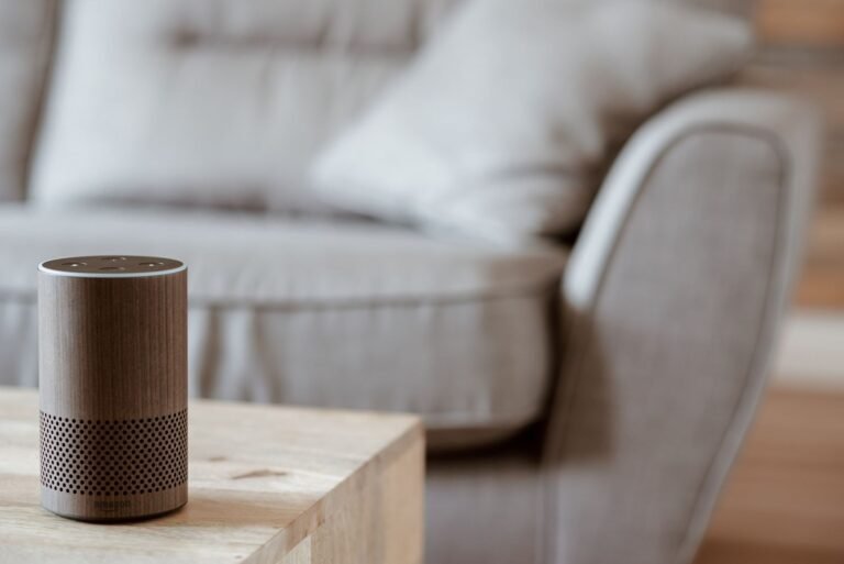 A modern smart speaker with an illuminated glowing ring on a dark background.