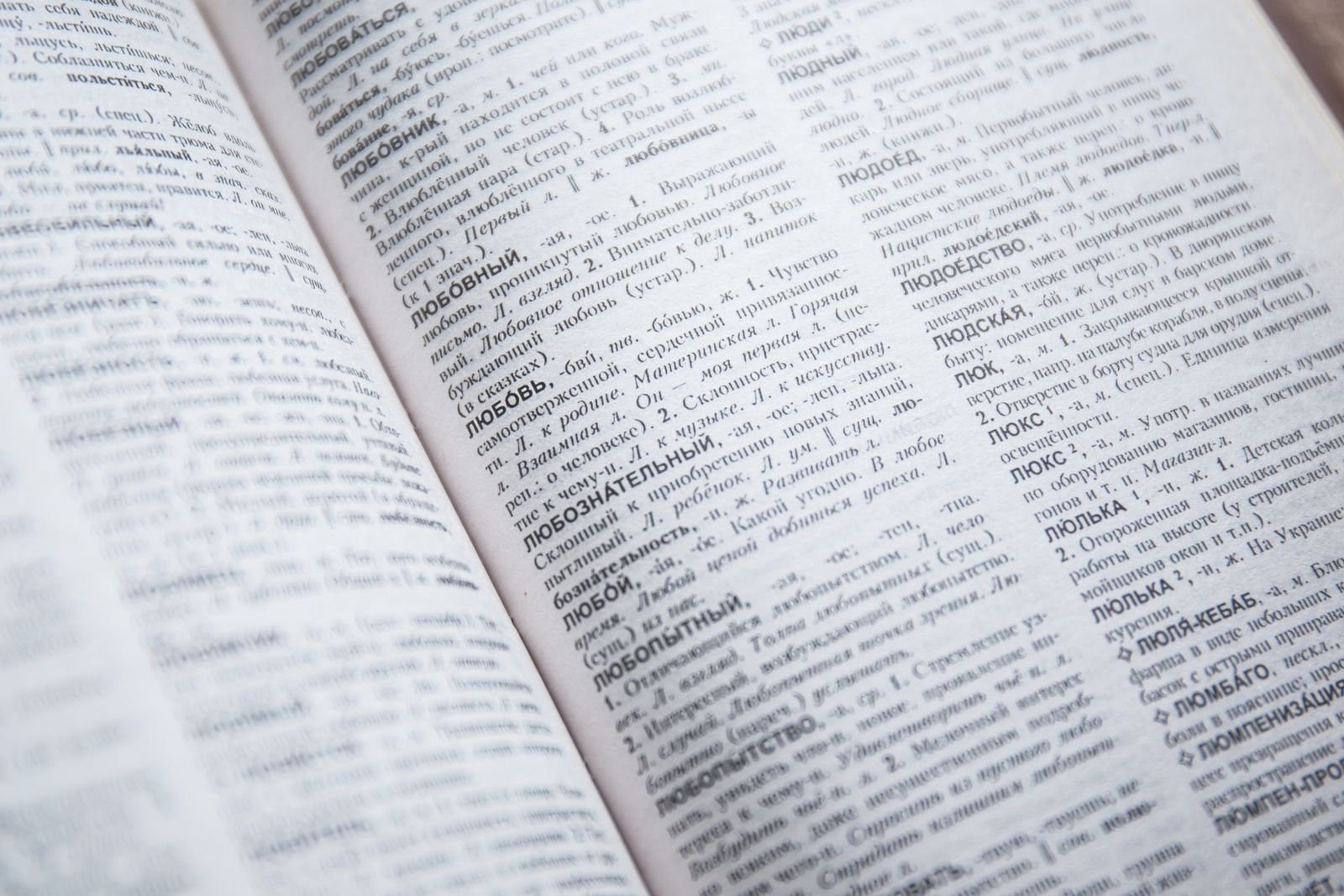 A close-up of an open Russian dictionary showing detailed entries and text.